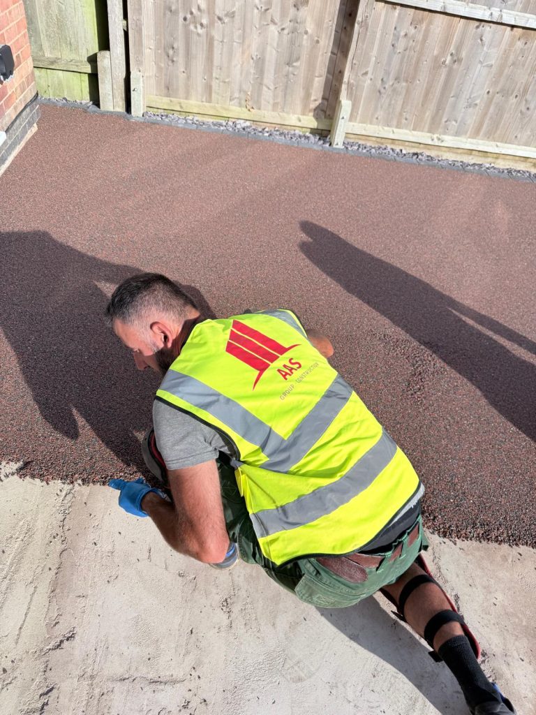 In-progress shot of an AAS Group Construction technician hand-troweling a new resin bound surface in Wellingborough, Northamptonshire