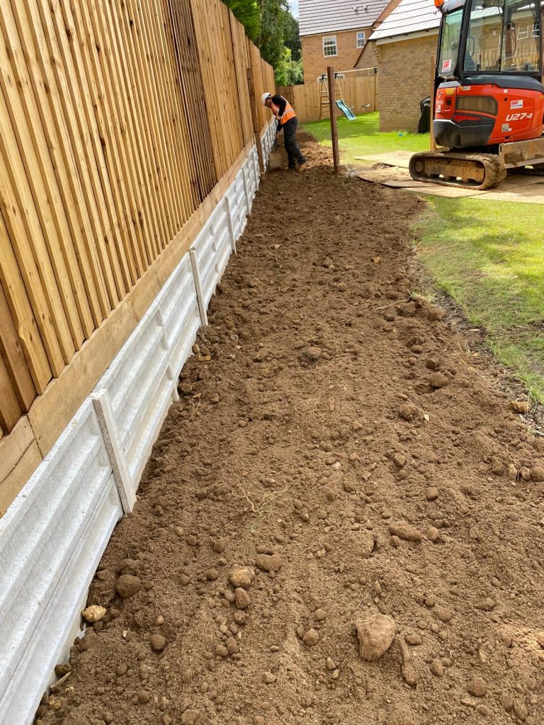 Newly installed timber fence with concrete gravel boards and concrete posts next to a freshly leveled topsoil border