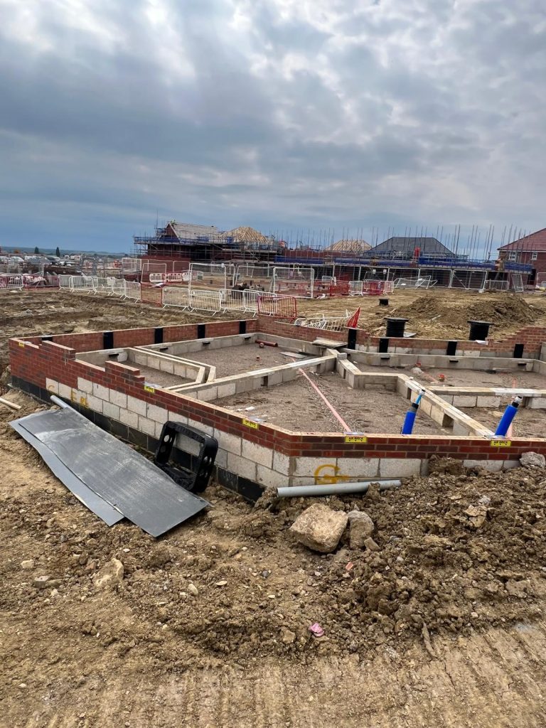 Wide view of new build plot foundation brickwork and utility duct installation on a housing development in Wellingborough