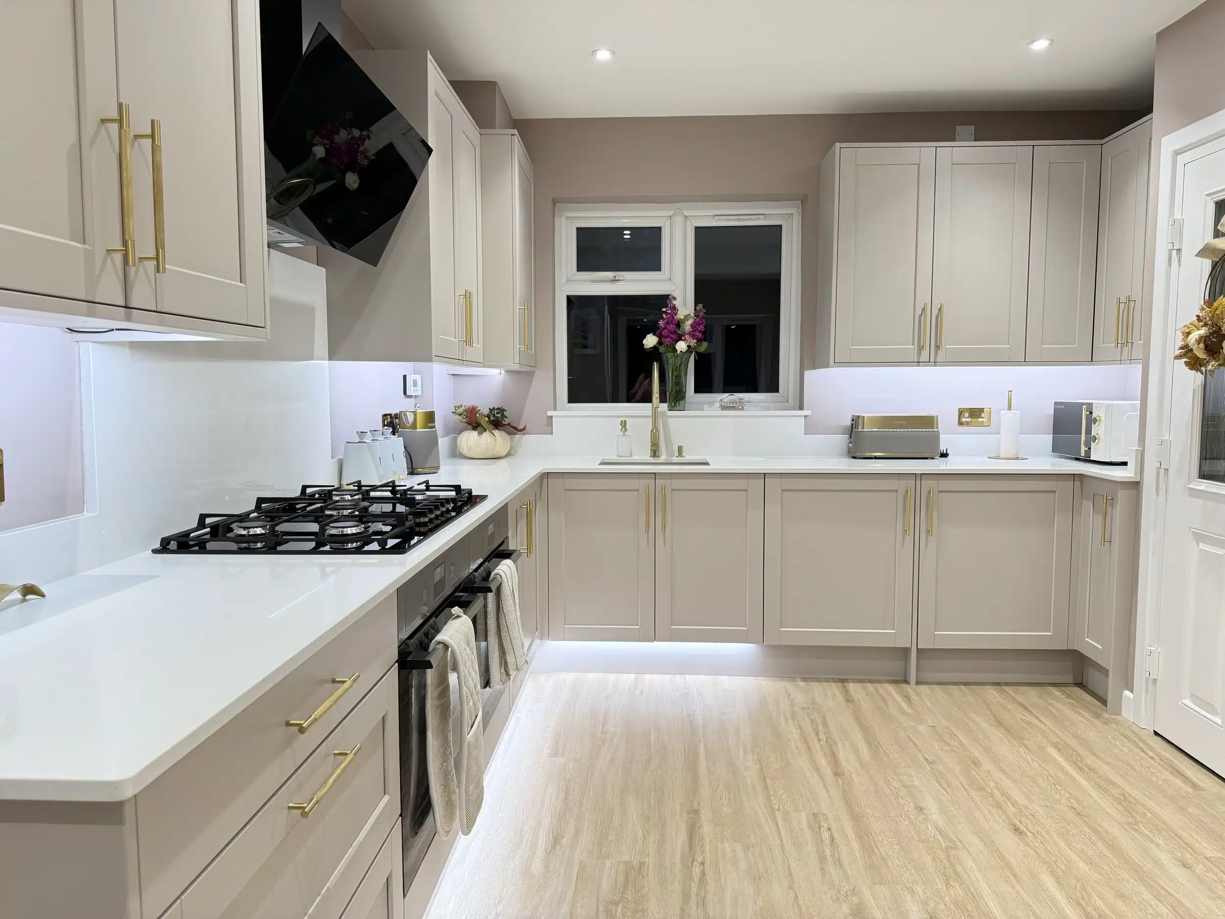 Modern cashmere shaker kitchen renovation with gold handles and white quartz worktops