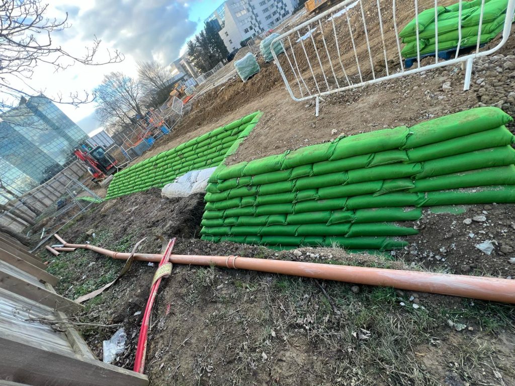 Civil engineering groundworks and green modular retaining wall construction with drainage pipes in Preston Deanery