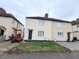 Before photo of a residential front garden and driveway renovation project in Rothwell, Northamptonshire, with a mini excavator on site