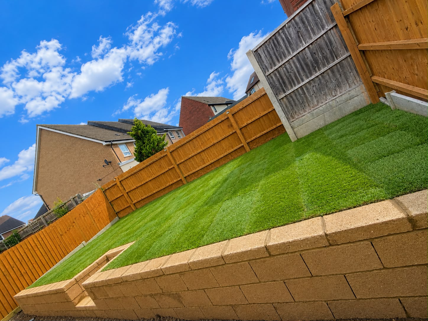 Completed 10m retaining wall with central steps and freshly laid turf lawn in Wellingborough
