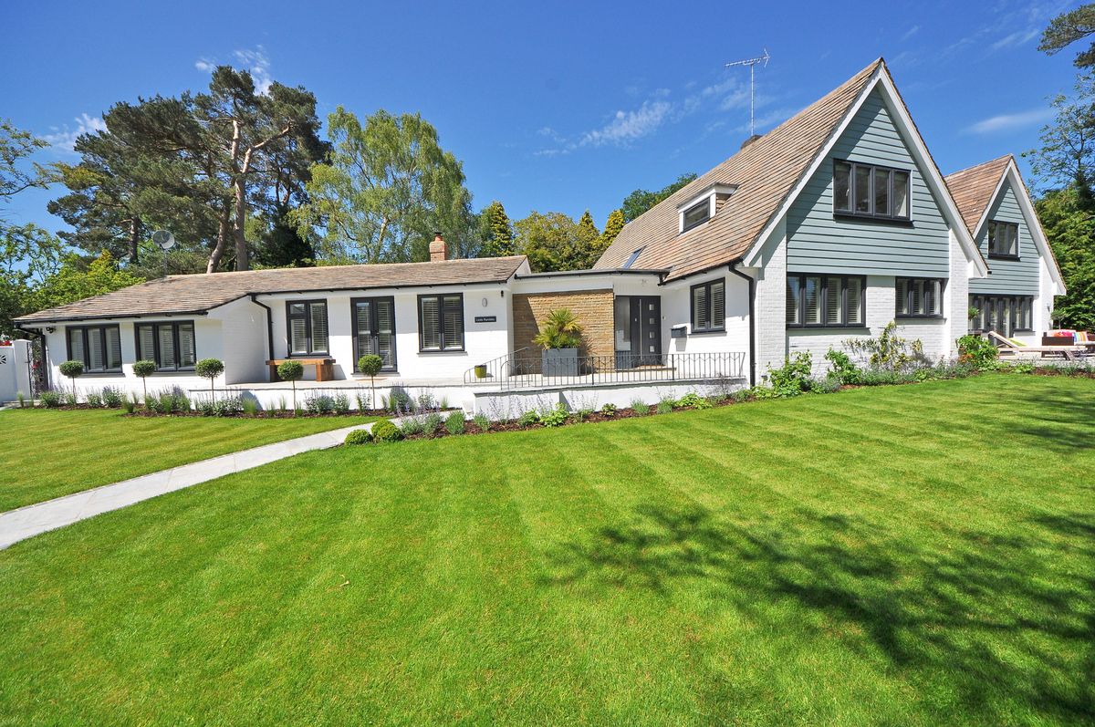 White UK chalet-style home with a single-storey extension and landscaped garden