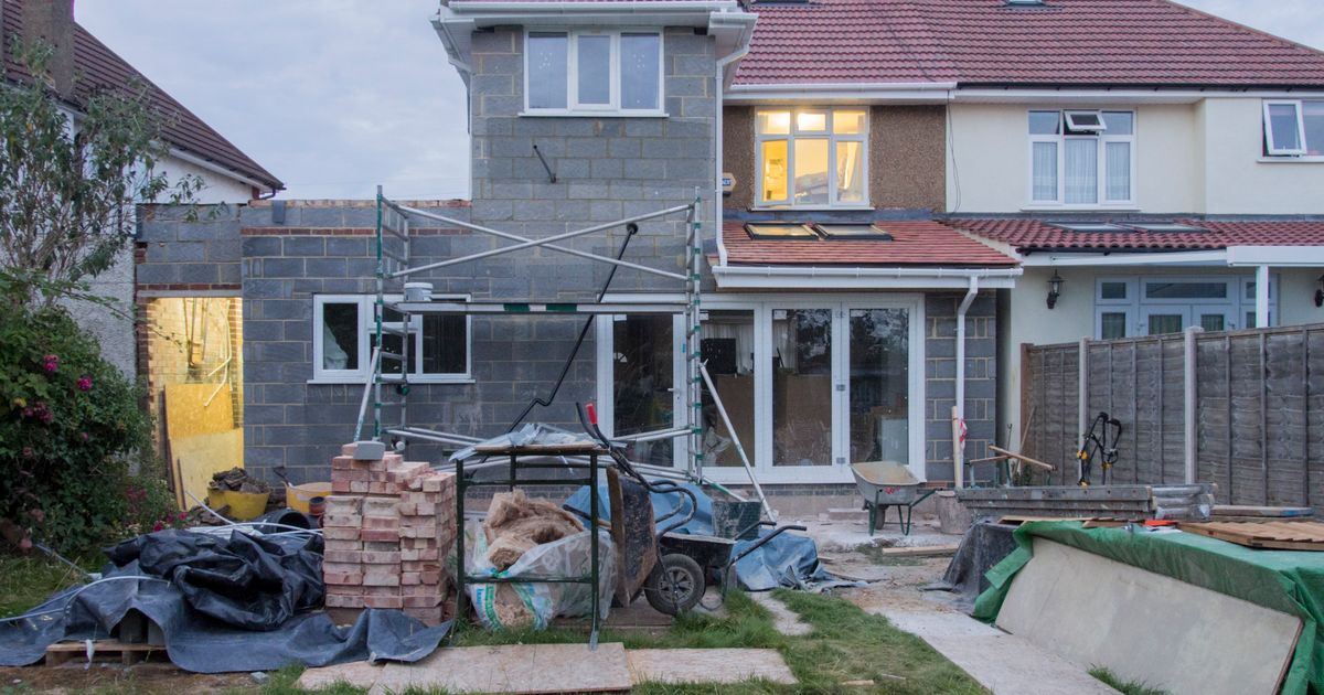 Suburban home undergoing major renovation with scaffolding and building materials visible
