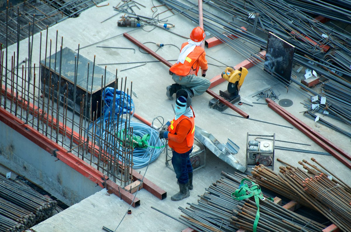Construction workers preparing steel reinforcement in an excavation pit before a concrete foundation pour